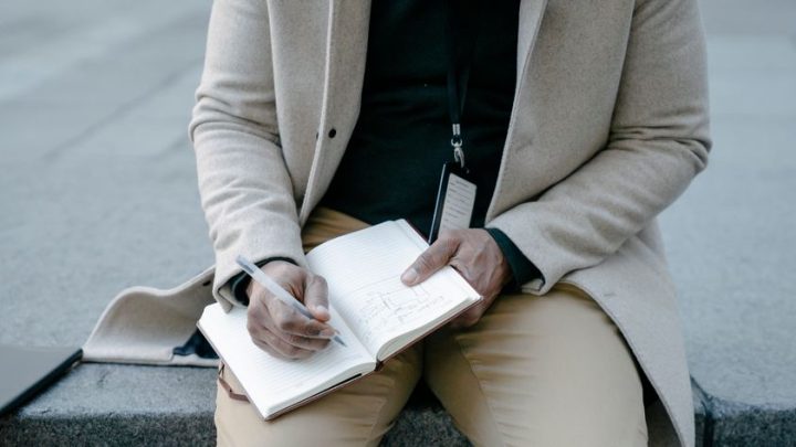 person writing notes notebook