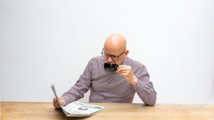 person reading paper morning coffee