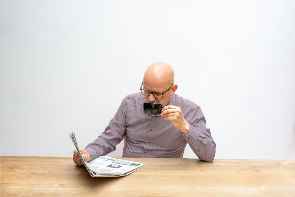 person reading paper morning coffee